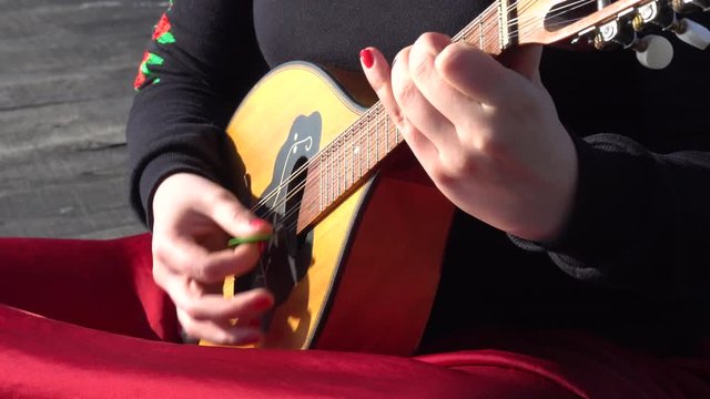 Woman wearing red dress playing mandoline