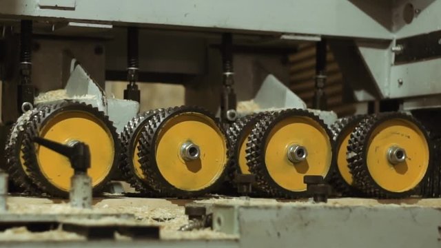 Spinning spiked wheels of plank refiner machine working on wood at sawmill production, close up