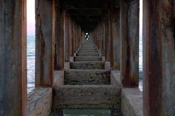 Fototapeta na wymiar Under the bridge walkway at the pier from the beach to the sea