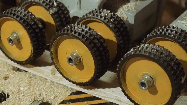 Rolling spiked wheels of plank refiner machine working on wood at sawmill factory, close up
