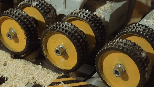 Spinning spiked wheels of board refiner machine working on wood at carpenter production, close up