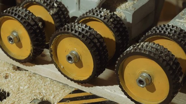 Rolling spiked wheels of board refiner machine working on wood at carpenter production, close up