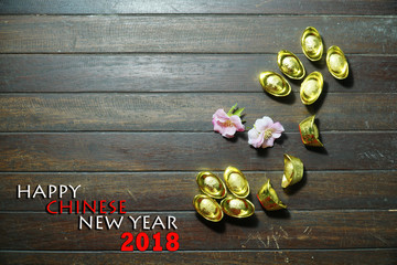 Chinese gold ingots flat lay  with a text HAPPY CHINESE NEW YEAR 2018 on a wooden background.