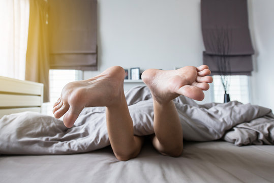 Close up of  barefoot under blanket,Feet and stretch lazily on the bed after waking up