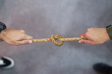 Tug War concept.Two Men pulling the rope with knot in opposite directions.
