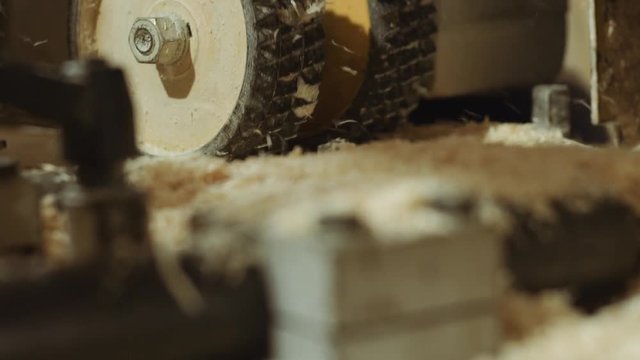 Rolling spiked wheels of board refiner machine working on wood at lumber factory, close up