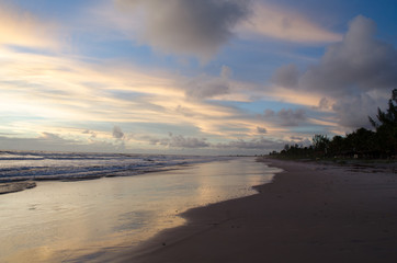 Fototapeta na wymiar view of the blue sky and full of morning clouds on a beach with sea water reaching in the sand.