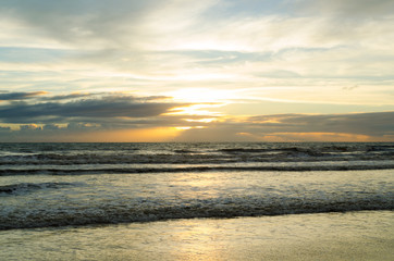 view of sunrise on a beach with the reflection of the sun in the sea water.