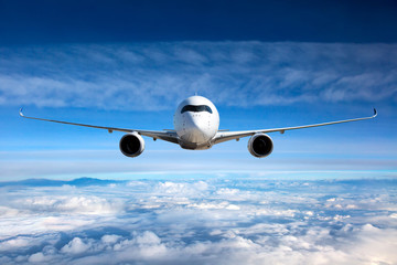 Obraz premium Widok z przodu samolotu w locie. Samolot pasażerski leci wysoko nad chmurami.