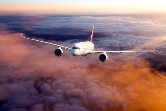 Sunset flight. The passenger wide body aircraft flies high above the colored clouds.