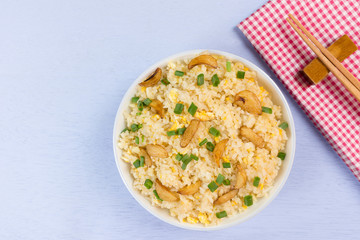 top view of garlic fried rice in a ceramic dish with chopsticks and napkin on light blue wooden background. homemade style healthy food concept.