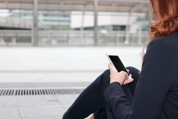 Mobile smart phone is being held on hands of business woman  against copy space background. City...