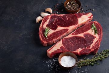 Raw fresh marbled meat Steak Ribeye Black Angus on black marble background. Beef with spices on a...