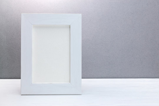 empty wooden white photo frame against grey background
