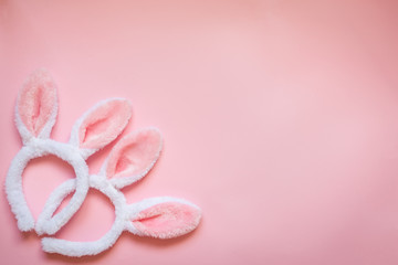 Top view of two white fluffy bunny ears over pink background. Easter concept. Copy space.