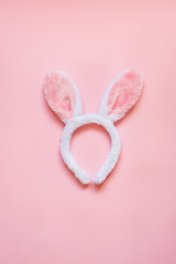 Top view of white fluffy bunny ears over pink background.