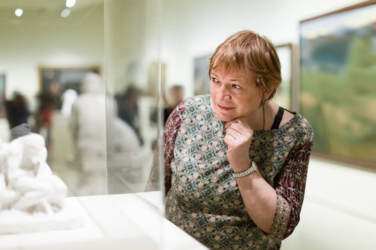 Happy pensioner woman watching at sculpture