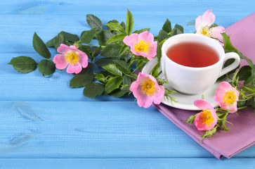 Cup of tea and wild rose flower on boards, copy space for text