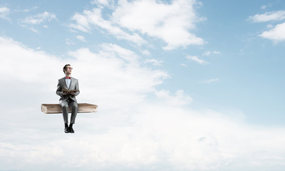 Young businessman or student floating in blue sky and studying the science