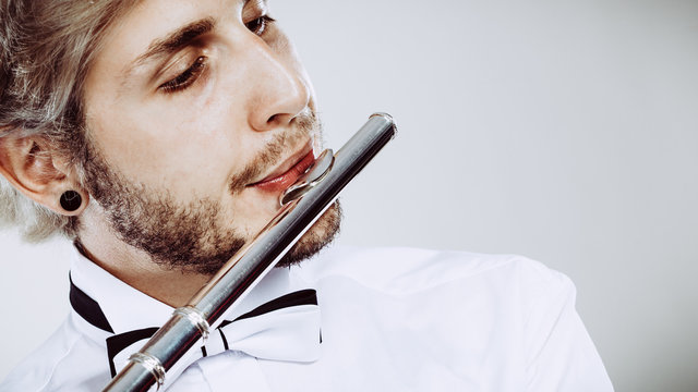 Male flutist playing his flute closeup
