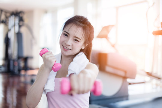beautiful and smart healthy asian young woman smile while workout at gym fitness center with blur background