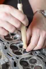 The mechanic restores the worn out car engine. grooving of cylinder valves