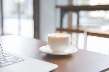 Coffee cup and laptop for business in coffee shop in the morning