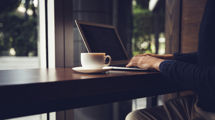 Selective focus of Side view laptop is on the work table in a conner office with morning light.