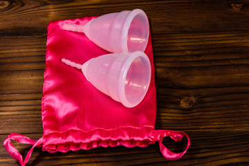 Two menstrual cups and cotton bag on a wooden table