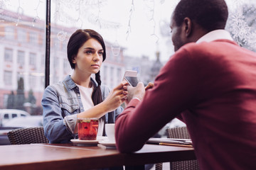 Huge offense. Upset sad nice woman sitting while gazing straight and carrying phone