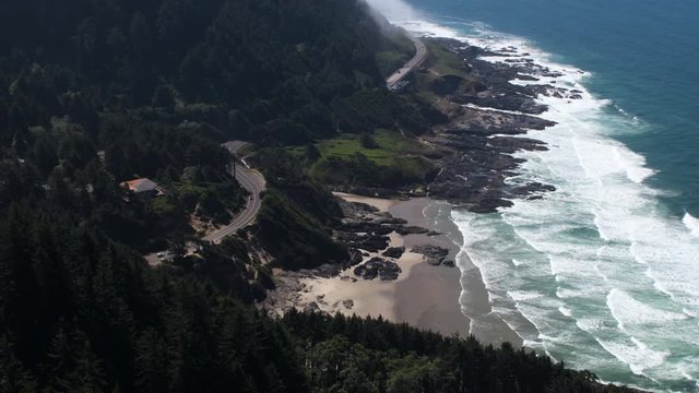 View of the coastline and highway 101 from the top of Cape Perpetua, a small patch of fog hugging the coastline in the distance.