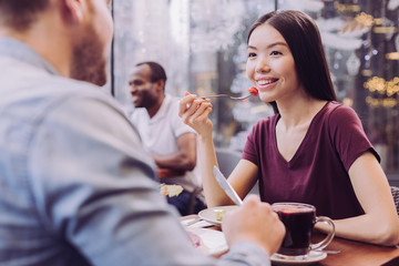 Great company. Smart pensive cheerful woman holding fork while looking at man and smiling