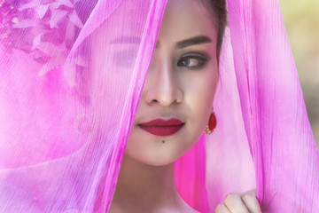 Beautiful Thai woman wearing traditional Thai dress with silk fabric cover her head