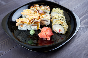 Sushi rolls with ginger and wasabi on a black plate