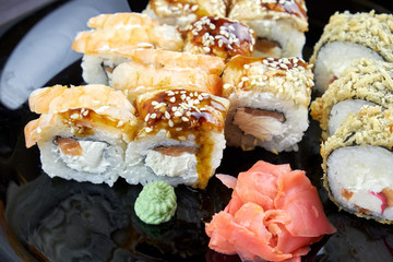 Sushi rolls with ginger and wasabi on a black plate