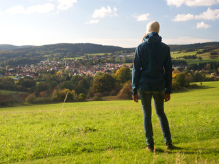 Wanderer im Herbst schaut auf Bergstadt in Thüringen
