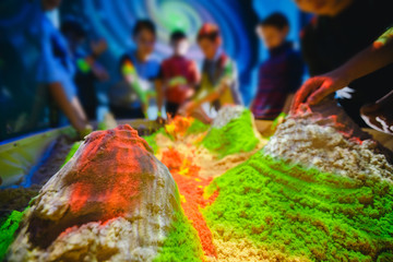 Children play with kinetic sand. Concept simulator of earth, volcanoes, relief and soil surface.