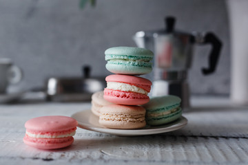 Macaroon. Macaron on gray neutral loft background, stand on plate of different colors. Wooden background.
