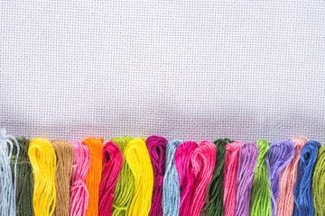 Colored thread for embroidery on white canvas. Copy spase.