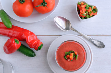 Gazpacho, tomato soup made from made of raw blended vegetables. Traditional Spanish cold soup in glass bowl on wooden table.Top view
