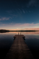 Savojärvi lake at midnight lit by moonlight and a pier on foreground in Kurjenrahka National Park,...