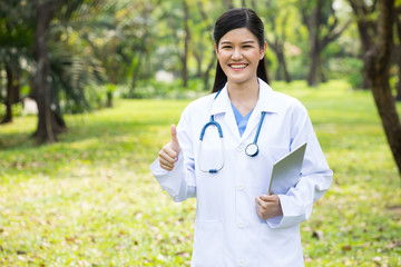 Portrait of Female doctor with thumbs up in park