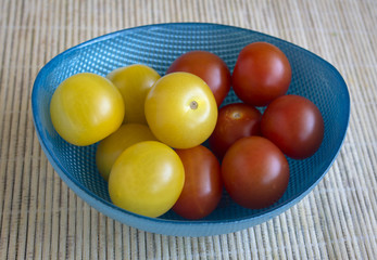 Yellow and red cherry tomatoes in a blue bowl.