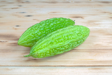 Fresh bitter melon or bitter gourd (Momordica charantia)  over pine wood grain