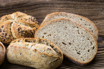 Different kinds of fresh bread on wooden table. Isolated assortment of bread on brown background.