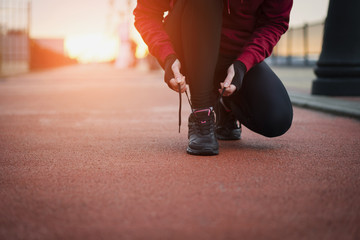 Fototapeta na wymiar The Runner woman ties the shoelaces before running. Healthy lifestyle.
