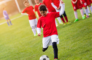 Fototapeta premium Boy kicking football on the sports field
