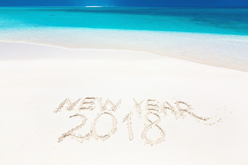 Inscription word NEW YEAR and numbers 2018 on sandy beach