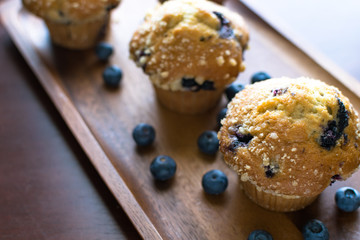 Blueberry muffins with fresh blueberries on wooden tray