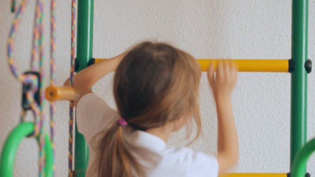 Young girl climbing up and down gymnastic complex